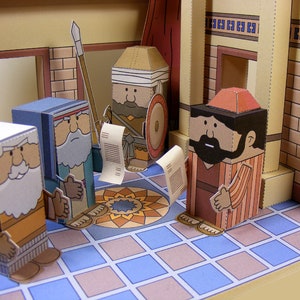 Puede incluir: Cuatro figuras de papel se encuentran de pie sobre un suelo de baldosas. Las figuras est&aacute;n vestidas con t&uacute;nicas marrones, azules y rojas. Sostienen rollos y una lanza. Las figuras est&aacute;n en una habitaci&oacute;n con una pared de ladrillo y una cortina roja.
