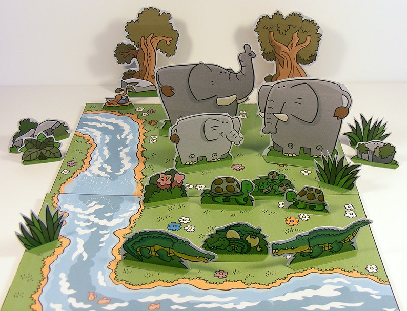 May include: A pop-up book with a jungle theme featuring a river, trees, elephants, and turtles. The book is made of paper and has a colorful design.