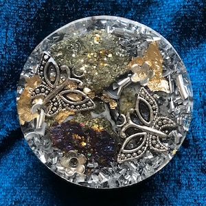 May include: A round, clear resin coaster with a silver butterfly design, gold leaf accents, and a mix of black, gold, and silver glitter.