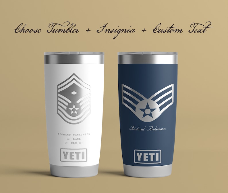 May include: Two stainless steel YETI tumblers with a silver insignia of an Air Force rank and a personalized name. The tumbler on the left is white and the tumbler on the right is blue.