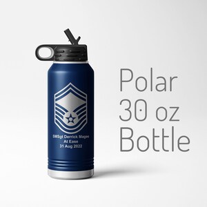 May include: A blue 30 ounce stainless steel water bottle with a black lid and a carrying handle. The bottle has a silver emblem of the Air Force rank of Senior Master Sergeant and the text "SMSgt Derrick Magee At Ease 31 Aug 2022".