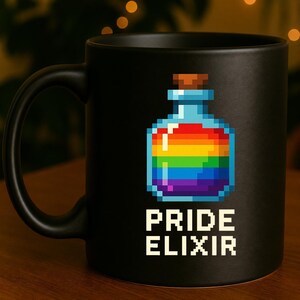 Könnte beinhalten: Ein mattschwarzer Keramikbecher mit einer Pixel-Art-Grafik einer Glasflasche, die mit einer regenbogenfarbenen Flüssigkeit gefüllt ist. Die Flasche hat einen braunen Korkverschluss. Unter der Grafik steht der Text PRIDE ELIXIR in weißer Schrift.