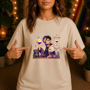 Könnte beinhalten: Ein beiges T-Shirt mit einer Grafik eines Charakters, der eine Zaubertrankflasche in Gelb, Weiß, Lila und Schwarz hält. Die Grafik enthält eine Tafel mit dem Text Mixing Magic, Not Gender und ein Banner mit Potions For Everyone.