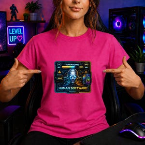 Könnte beinhalten: Ein magentafarbenes T-Shirt mit einem futuristischen Grafikdesign. Das Design zeigt ein Robotergesicht, einen Fortschrittsbalken und den Text "HUMAN SOFTWARE" und "UPGRADING". Das T-Shirt hat eine leuchtende Farbe.
