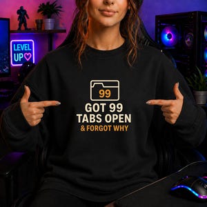 Peut inclure: Sweat-shirt noir avec l'inscription "GOT 99 TABS OPEN & FORGOT WHY". Le design comprend une icône de dossier avec le chiffre 99. C'est un vêtement décontracté.
