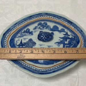 May include: A blue and white porcelain oval serving dish with a lid. The lid has a blue and white floral design and a knob in the center. The dish is 9 inches long.