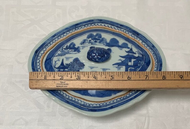 May include: A blue and white porcelain oval serving dish with a lid. The lid has a blue and white floral design and a knob in the center. The dish is 9 inches long.