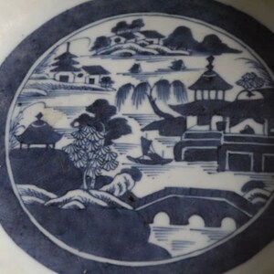 K&ouml;nnte beinhalten: Eine wei&szlig;e Porzellanschale mit einem blauen und wei&szlig;en Design einer chinesischen Landschaft mit einer Br&uuml;cke, B&auml;umen und Geb&auml;uden.