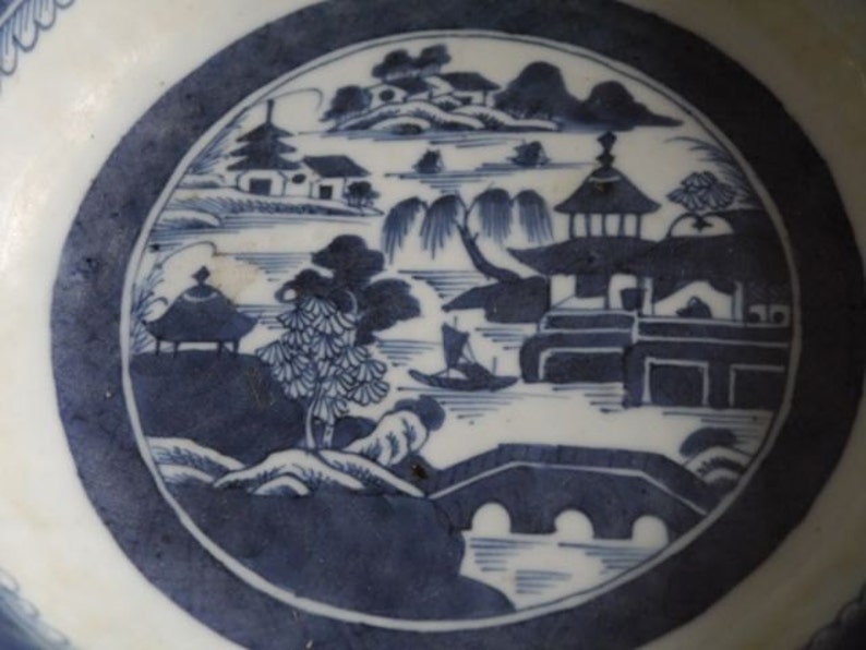 K&ouml;nnte beinhalten: Eine wei&szlig;e Porzellanschale mit einem blauen und wei&szlig;en Design einer chinesischen Landschaft mit einer Br&uuml;cke, B&auml;umen und Geb&auml;uden.