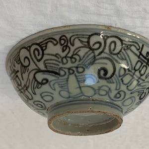 Puede incluir: Un cuenco de cerámica blanca con un diseño azul y negro. El cuenco tiene un patrón de remolinos de nubes y otras formas abstractas.