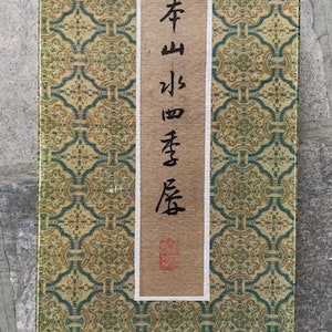 Könnte beinhalten: Ein Vintage-Buch mit einem grün-goldenen Muster auf dem Einband. Der Titel auf dem Rücken ist in schwarzer Tinte geschrieben und lautet "Qing Shan Jiu Shi Fang".