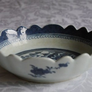 K&ouml;nnte beinhalten: Eine wei&szlig;e Porzellanschale mit einem gewellten Rand und einem blauen und wei&szlig;en Blumendesign. Die Schale hat ein blaues und wei&szlig;es Blumendesign auf der Innenseite und einen blauen Rand.
