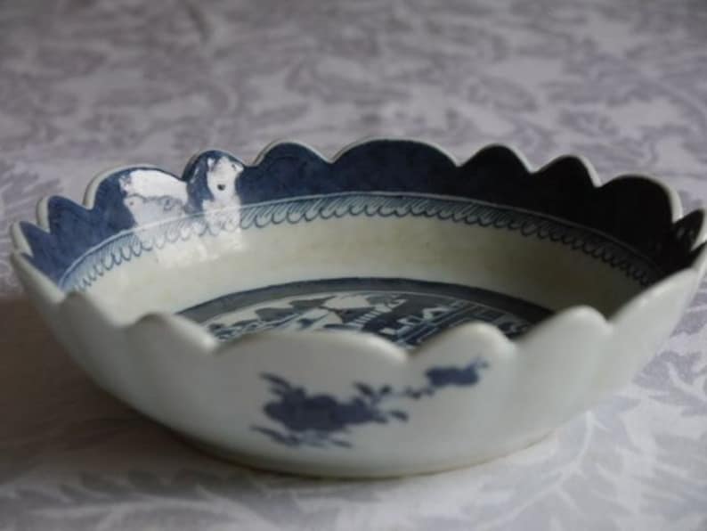 K&ouml;nnte beinhalten: Eine wei&szlig;e Porzellanschale mit einem gewellten Rand und einem blauen und wei&szlig;en Blumendesign. Die Schale hat ein blaues und wei&szlig;es Blumendesign auf der Innenseite und einen blauen Rand.