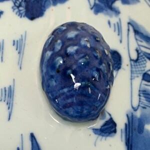 May include: Close-up of a blue and white ceramic knob with a textured surface. The knob is round and has a glossy finish.