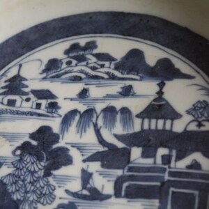 K&ouml;nnte beinhalten: Ein blauer und wei&szlig;er Porzellanteller mit einem traditionellen chinesischen Landschaftsdesign. Die Szene zeigt eine Pagode, H&auml;user, B&auml;ume und einen Fluss. Der Teller ist mit einer blauen und wei&szlig;en Glasur verziert.