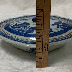 May include: A blue and white porcelain serving dish with a lid. The dish has a scalloped edge and a gold trim. The lid has a knob on top. The dish is 5 inches in diameter.