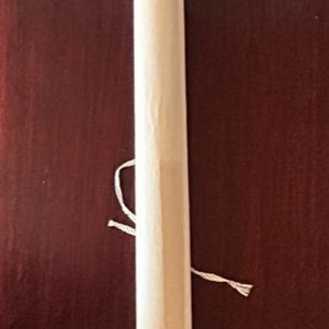 Könnte beinhalten: Eine aufgerollte Schriftrolle mit Holzstäben an jedem Ende und einer weißen Schnur zum Binden.