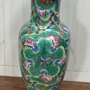 以下が含まれることがあります： 黒色の土台に緑と白の磁器製のテーブルランプ。蓮の花と鳥が描かれた花柄のデザイン。ランプは多色の花柄で装飾されている。