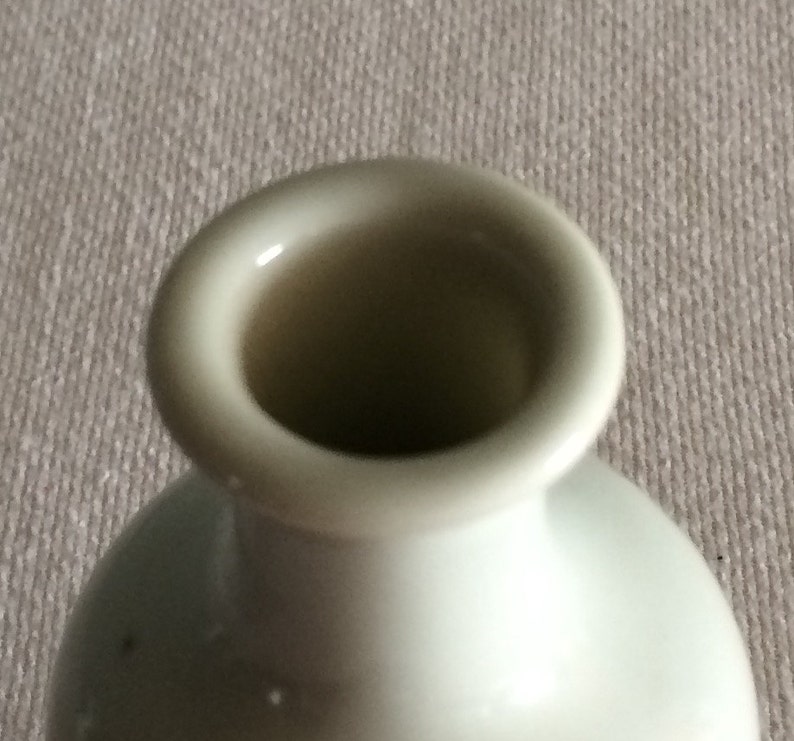 Może przedstawiać: Biały ceramiczny wazon z szerokim otworem. Wazon ma gładkie, błyszczące wykończenie.