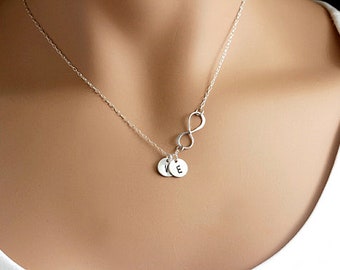 May include: A silver necklace with an infinity symbol charm and two small round charms with the letters "K" and "E" engraved on them.