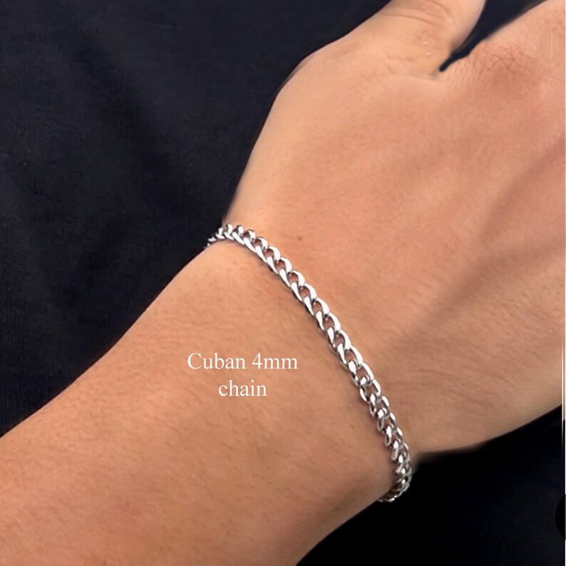May include: A silver Cuban chain bracelet with a 4mm width. The bracelet is on a person's wrist.