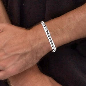 May include: A silver curb chain bracelet with a classic design.