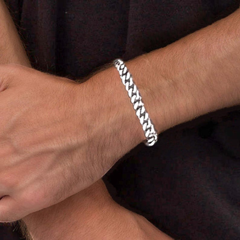 May include: A silver curb chain bracelet with a classic design.