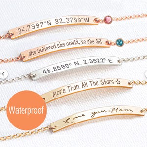 May include: Four gold and silver bracelets with different engraved messages. The top bracelet is rose gold with the text "34.7997°N 82.3799°W". The second bracelet is gold with the text "she believed she could, so she did". The third bracelet is silver with the text "48.8566° N, 2.3522° E". The bottom bracelet is gold with the text "More Than All The Stars ☆".