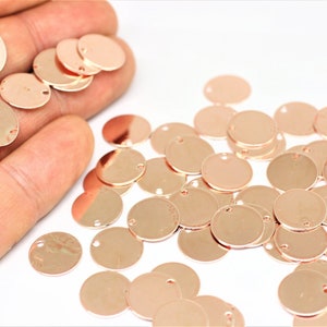 May include: A large quantity of rose gold colored metal circles with a small hole in the center. The circles are scattered on a white surface.