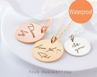 May include: Three circular pendant necklaces in rose gold, gold, and silver tones. Each pendant features custom engraved handwriting. The rose gold pendant reads Dream big, the gold reads Love you Phil, and the silver reads Be you. Includes a Waterproof label.