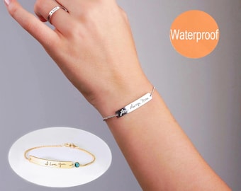 Può includere: Un bracciale color argento con catenina sottile e una barretta rettangolare incisa in corsivo, abbinato a un anello coordinato. Un riquadro mostra una versione dorata del bracciale con una piccola pietra blu e la scritta I Love You.