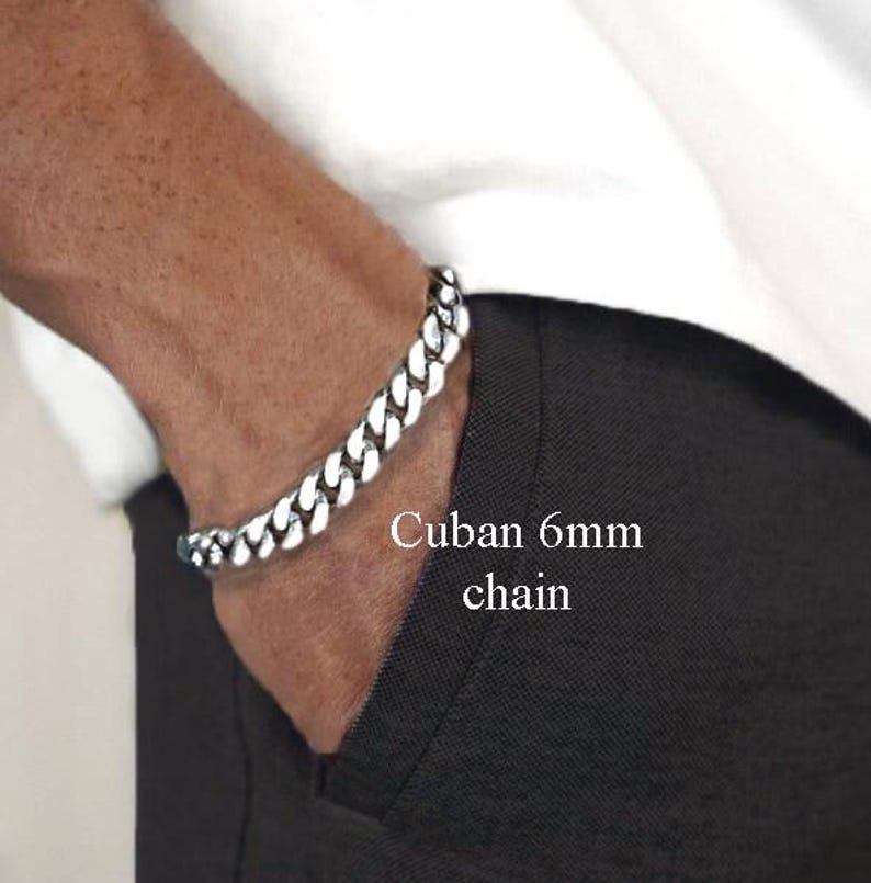 May include: A silver Cuban chain bracelet with a 6mm width. The bracelet is worn on a person's wrist.