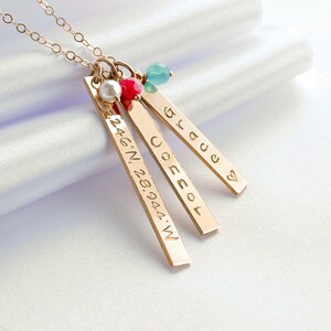 Op de afbeelding: Gouden ketting met drie staafvormige hangers. De hangers zijn gegraveerd met de woorden "Grace", "Jocelyn" en de co&ouml;rdinaten "24.46.N. 28.94.44.W".