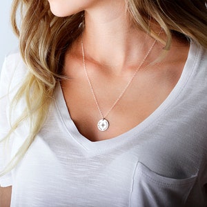 May include: A silver necklace with a round pendant featuring a compass design and the words "Always Find Your Way".