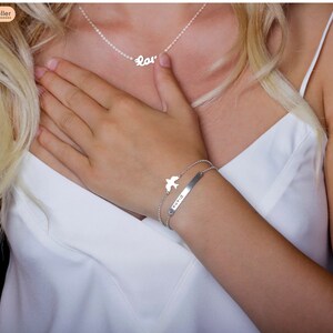 May include: A silver necklace with the word "Love" and a silver bracelet with a bird charm and the word "Dream" on a bar.