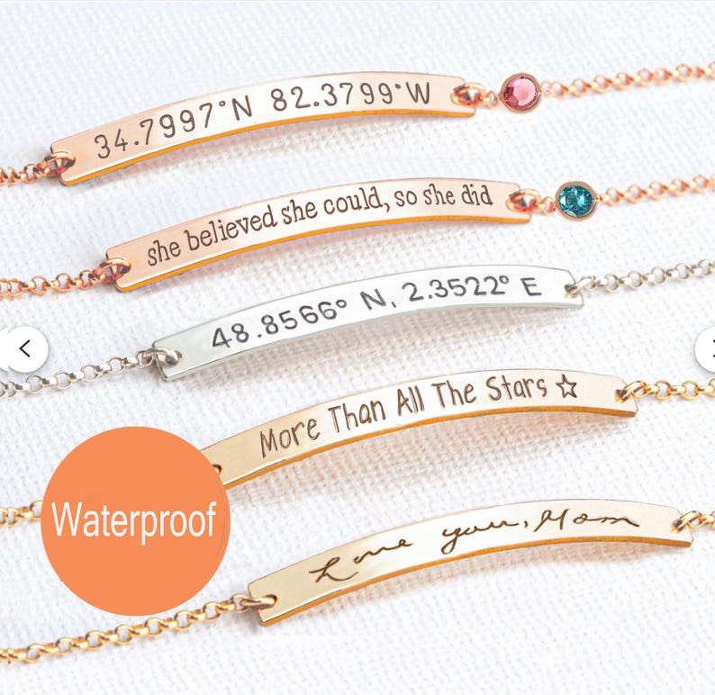 May include: Five metal chain bracelets with curved horizontal bars. The bars feature engraved text: 34.7997 N 82.3799 W, she believed she could, so she did, 48.8566 N, 2.3522 E, More Than All The Stars, and Love you, Mom. Two include small colored stones.