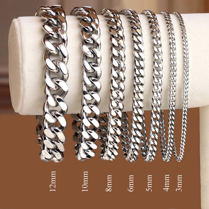 May include: Seven silver curb chain bracelets of varying widths, from 3mm to 12mm, displayed on a white surface. The bracelets are arranged from smallest to largest, with the width of each bracelet labeled below it.