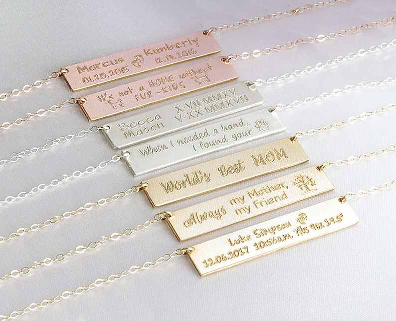 May include: A set of six gold, silver, and rose gold necklaces with personalized bar pendants. The pendants feature engraved messages such as "World's Best Mom", "It's not a home without fur-kids", and "When I needed a hand, I found your's".