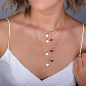 May include: Four gold-toned necklaces with delicate chains and small circular pendants. The necklaces are layered at different lengths, labeled with text indicating 15 inches, 16 inches, 18 inches, and 20 inches to show the varying chain sizes.