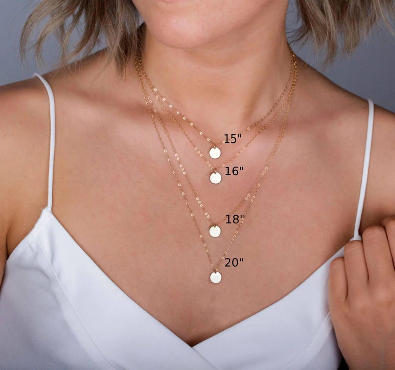 May include: Four gold-toned necklaces with delicate chains and small circular pendants. The necklaces are layered at different lengths, labeled with text indicating 15 inches, 16 inches, 18 inches, and 20 inches to show the varying chain sizes.