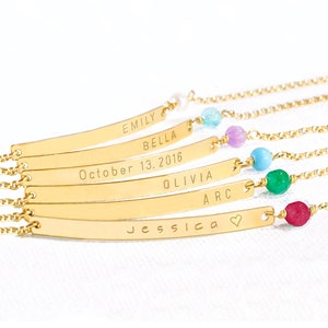 May include: Six gold bar bracelets with different names and dates engraved on them. Each bracelet has a small gemstone bead in a different color: light blue, purple, turquoise, green, and red.