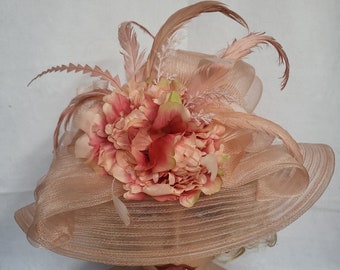 An elegant peach hat adorned with delicate flowers and feathers
