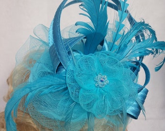 A stunning turquoise fascinator featuring elegant feathers.