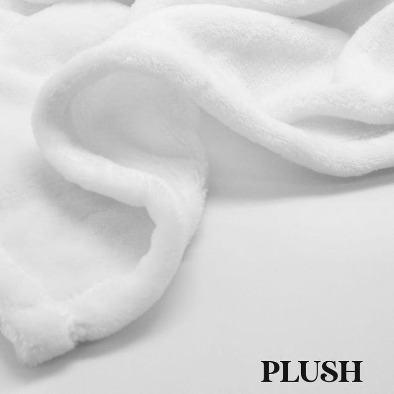 May include: Close-up of a soft, white plush blanket. The blanket is folded and draped, showing the texture of the fabric. The word "PLUSH" is printed in a bold, black font at the bottom right corner.