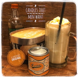 Könnte beinhalten: Eine Kerze in einer Metalldose mit einem gelben und orangefarbenen Etikett, auf dem "Scented Candle Boston Cooler" und "www.gorillacandles.com" steht. Die Kerze steht auf einer Holzoberfläche neben einem Glas Eiscreme und einem Behälter mit Eiscreme.
