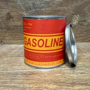 Könnte beinhalten: Eine rot-gelbe Metallkanne mit dem Wort "GASOLINE" in großen, fetten Buchstaben. Die Dose ist mit "12 U.S. Pint" beschriftet und hat einen silbernen Deckel daneben. Auf der Unterseite der Dose steht "www.GORILLACANDLES.COM".