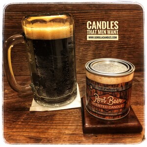 Peut inclure: Une bougie brune et blanche dans une bo&icirc;te en m&eacute;tal avec le texte "Old Fashioned Root Beer Scented Candle" et le site web "www.gorillacandles.com". La bougie est &agrave; c&ocirc;t&eacute; d'une tasse en verre remplie d'un liquide brun fonc&eacute;.