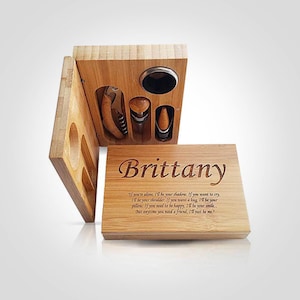 Puede incluir: Un juego de herramientas para vino de madera con sacacorchos, tapón y vertedor. El juego está personalizado con el nombre "Brittany" y una cita. La caja es de madera clara.