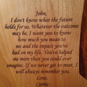 K&ouml;nnte beinhalten: Holztafel mit graviertem Text. Der Text lautet: &bdquo;John, ich wei&szlig; nicht, was die Zukunft f&uuml;r uns bereith&auml;lt... Love, Carrie.&ldquo;