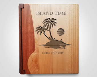 Könnte beinhalten: Fotoalbum aus Holz mit einer lasergeschnittenen tropischen Insel-Szene. Auf dem Cover stehen die Worte "ISLAND TIME" und "GIRLS TRIP 2019". Das Album hat ein zweifarbiges Holzdesign mit einem dunkelbraunen Rücken und einem hellbraunen Einband.